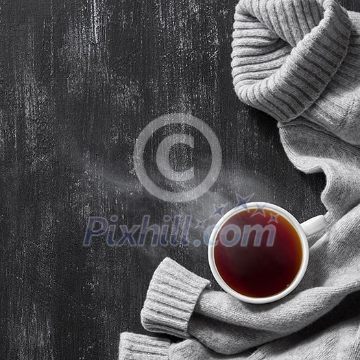 top view image of grey cozy knitted sweater with to cup of coffee on a wooden black table