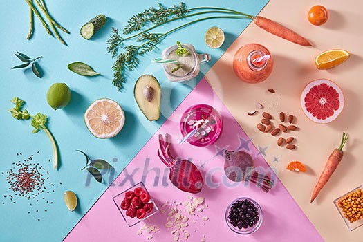 Orange, green and red smoothies from colorful natural vegetables and fruits in a glass bottles with plastic straws on a tricolor background. Top view.
