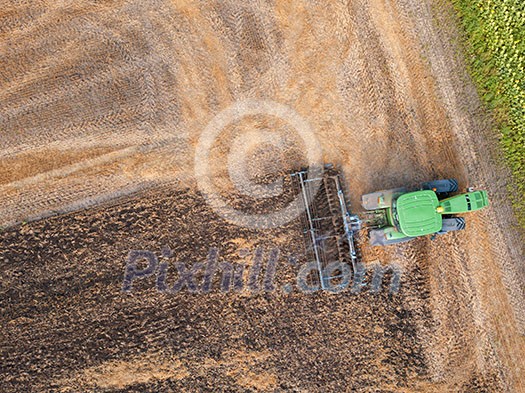 Plowing the ground after harvesting on the field in the autumn time. Aerial view from the drone of the field after harvest