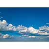 White fluffy clouds in the blue sky at sunset in the summer day. Nature weather, cloudy blue sky.