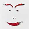 A person's face made up of different kinds of peppers - pods of red chili peppers, black and fragrant - nose, eyes, eyebrows, lips on a white background. Food smile concept.