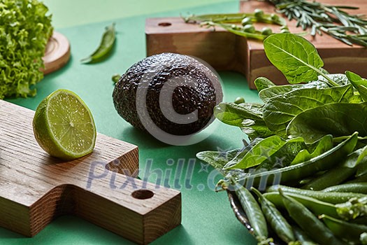Natural organic green vegetables for preparing a vegetarian salad on a wooden board on agreen background . Concept of natural healthy food.
