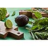 Natural organic green vegetables for preparing a vegetarian salad on a wooden board on agreen background . Concept of natural healthy food.