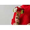 Red, green, white flowers of the Ranunculus. Girl holding a tender bouquet in the hands on a gray background with copy space. Mothers Day