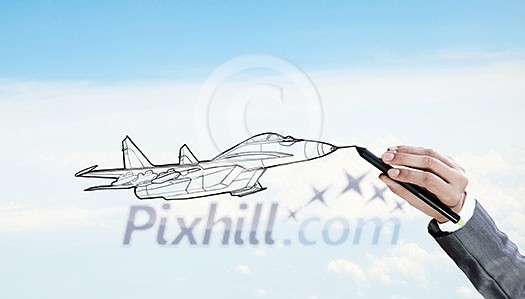 Person drawing airplane model on sky background