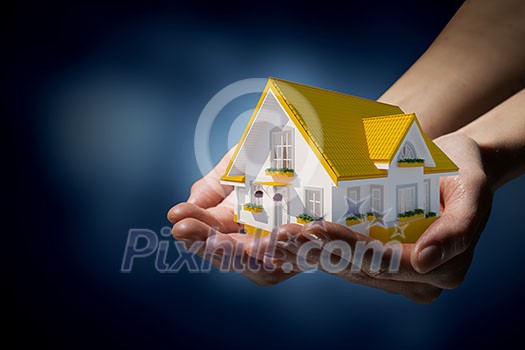 Human hands holding model of dream house