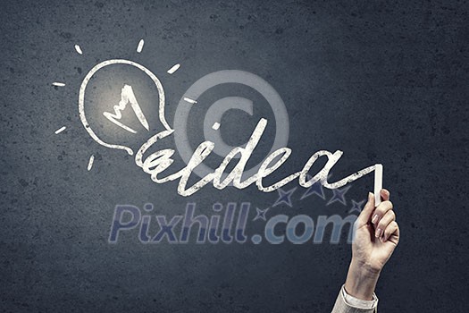 Human hand darwing light bulb as idea concept with chalk Human hand darwing light bulb as idea concept with chalk