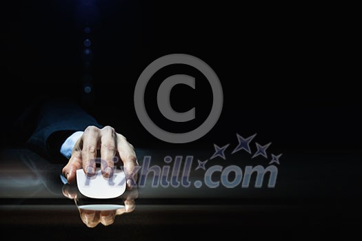 Hand of businessman in suit on dark background using wireless computer mouse