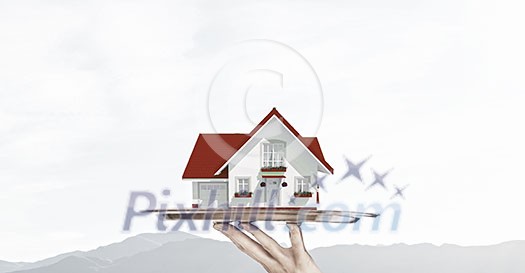 Hand of waiter offering house model on tray Hand of waiter offering house model on tray