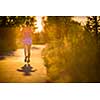 Young woman running outdoors on a lovely sunny summer evening (shallow DOF; color toned image)