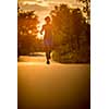 Young woman running outdoors on a lovely sunny summer evening (shallow DOF; color toned image)