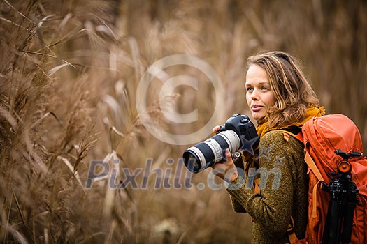 Pretty, female photographer taking pictures outdoor on a lovely autumn day - shallow DOF, color toned image