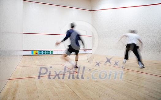 Squash players in action on a squash court (motion blurred image; color toned image) Squash players in action on a squash court (motion blurred image; color toned image)