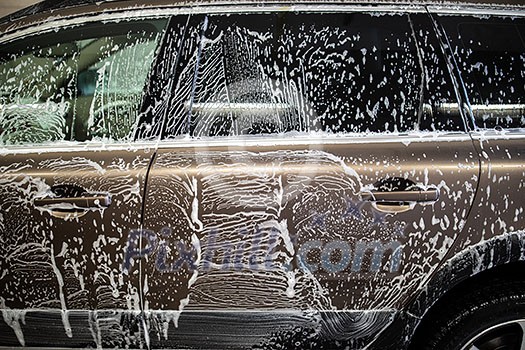 Car in a carwash covered with shampoo