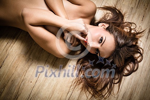 Attractive brunette lying on the floor in a seductive pose