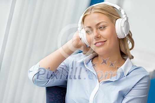 Woman in headphones sitting at desk in office Woman in headphones sitting at desk in office