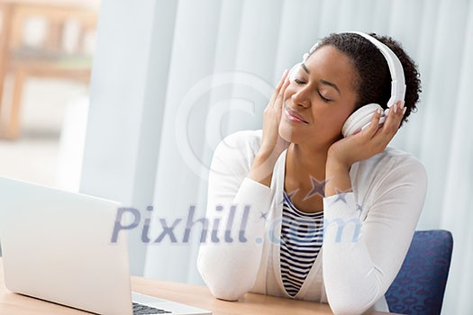 Woman in headphones sitting at desk in office Woman in headphones sitting at desk in office