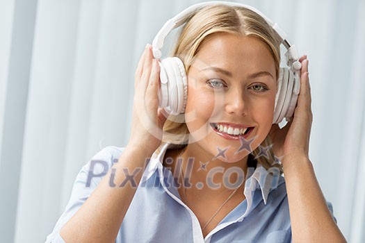Woman in headphones sitting at desk in office Woman in headphones sitting at desk in office