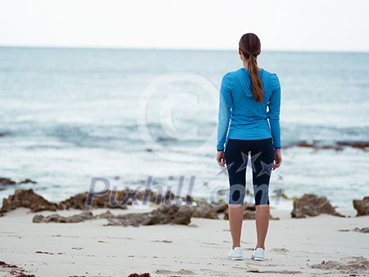 Sporty young woman standing in front of the ocean Sporty young woman standing in front of the ocean