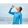 Sporty young woman drinking water on the sea coast