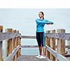 Sporty young woman stretching next to the sea coast