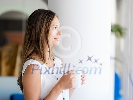 A young woman having coffee in office A young woman having coffee in office