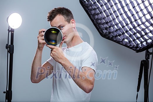 Young pro photographer with digital camera - DSLR and a huge telephoto lens in her well equiped studio, taking photos (color toned image; shallow DOF) Young pro photographer with digital camera - DSLR and a huge telephoto lens in her well equiped studio, taking photos (color toned image; shallow DOF)