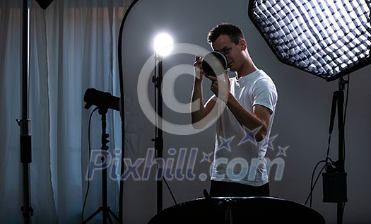 Young pro photographer with digital camera - DSLR and a huge telephoto lens in her well equiped studio, taking photos (color toned image; shallow DOF) Young pro photographer with digital camera - DSLR and a huge telephoto lens in her well equiped studio, taking photos (color toned image; shallow DOF)