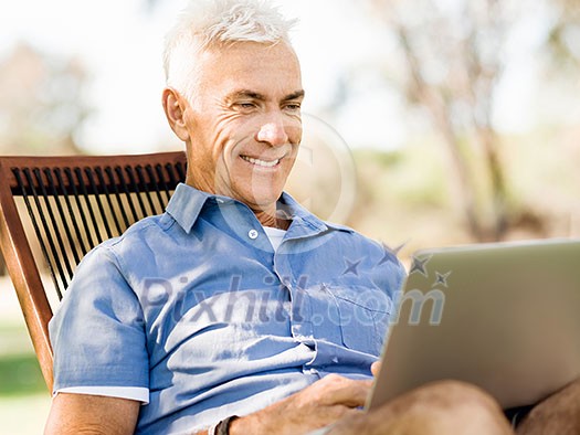 Handsome senior man with notebook sitting in the park