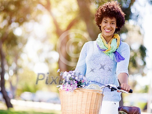 Happy young woman with bicycle in the park