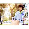 Happy young woman with bicycle in the park