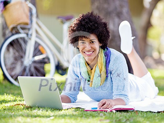 Woman working outdoors in park with laptop