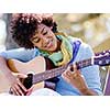 Young pretty woman playing guitar in park