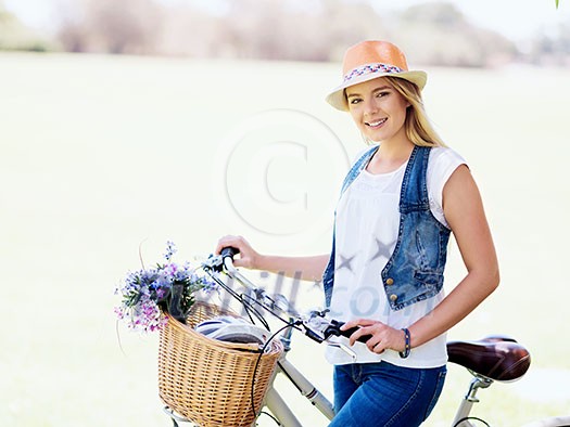 Happy young woman with bicycle in the park