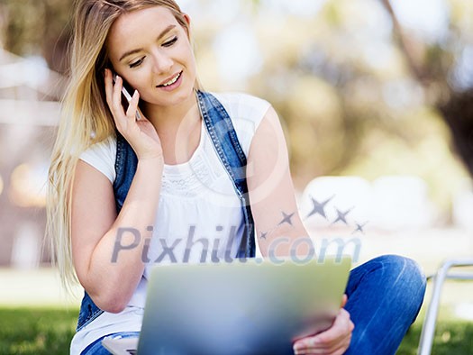Woman working outdoors in park with laptop