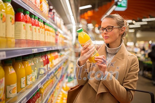 Pretty, young woman shopping for her favorite fruit juice/smoothie at a grocery store Pretty, young woman shopping for her favorite fruit juice/smoothie at a grocery store