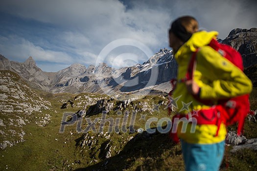 Pretty, young female hiker walking in high mountains (shallow DOF)