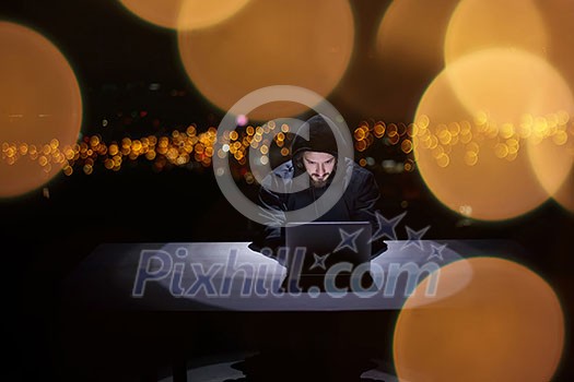 Young talented hacker using laptop computer while working in dark office with big city lights in the background at night Young talented hacker using laptop computer while working in dark office with big city lights in the background at night