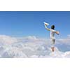 Back view of a girl playing with paper airplane against the sky, standing on clouds