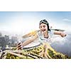 Joyful girl flying with self-made paper wing, making selfie, cityscape upper view
