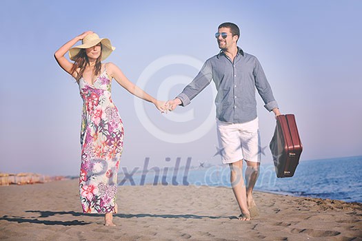 couple on beach with travel bag representing freedom and funy honeymoon concept