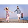 couple on beach with travel bag representing freedom and funy honeymoon concept