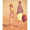 couple on beach with travel bag representing freedom and funy honeymoon concept