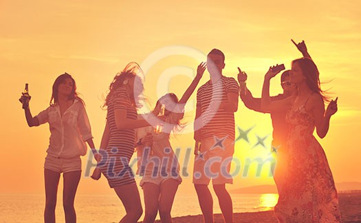 Group of young people enjoy summer party at the beach on beautiful sunset Group of young people enjoy summer party at the beach on beautiful sunset