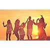 Group of young people enjoy summer  party at the beach on beautiful sunset