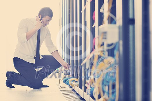 young business man computer science engeneer talking by cellphone at network datacenter server room asking for help and fast solutions and services young business man computer science engeneer talking by cellphone at network datacenter server room asking for help and fast solutions and services