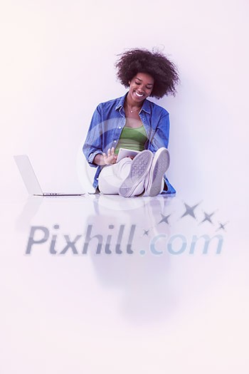 Portrait of happy young african american woman sitting on floor with laptop