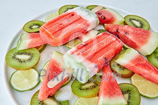 Berry healthy ice cream lolly of lime, watermelon, kiwi ildom in a plate on a gray background. Cold dessert