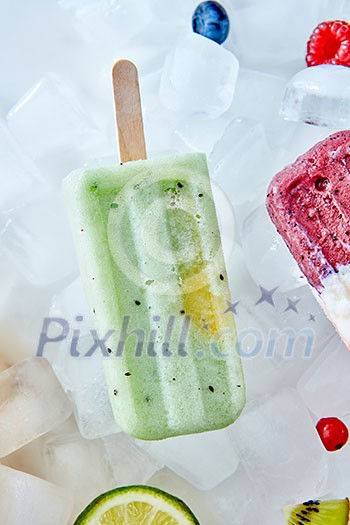 Detox, healthy green smoothie popsicles over the ice with slice lime, berries and kiwi, flat lay. Summer mood. Detox, healthy green smoothie popsicles over the ice with slice lime, berries and kiwi, flat lay. Summer mood.