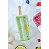 Detox, healthy green smoothie popsicles over the ice with slice lime, berries and kiwi, flat lay. Summer mood.